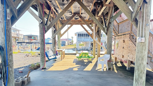 Una struttura in legno con pavimento in cemento, tavoli da picnic e panche.