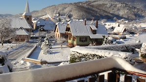 Een besneeuwd dorpje met traditionele huizen, een kerk en een berg op de achtergrond.