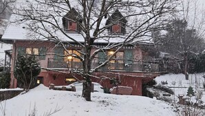 Een gebouw bedekt met sneeuw, met een opvallende toren, een boom ervoor en een besneeuwd landschap.