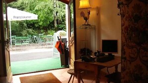A room with a desk, a lamp, a chair, and a view of the outside. - Hotel & Restaurant Tonihof (Eschenlohe)