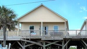 A two-story building with a balcony, a wooden deck, and a sign indicating it is for rent. - Blue Water Villa B - Coastal Realty Group (Grand Isle)