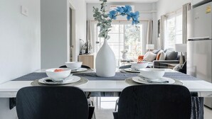 A modern dining area with a white table, black chairs, and a decorative vase. - Discover Chiang Mai from Cheerful Contemporary Cottage (Muang Chiang mai)