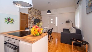 A modern kitchen with a built-in stove, a fruit bowl on the counter, and a dining area with a table and chairs. - Luxury Villa Jasmina with heated pool by the sea!!! (Omis)