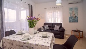 A dining area with a table set for four, a sofa, and a painting of a sailboat. - Luxury Villa Jasmina with heated pool by the sea!!! (Omis)