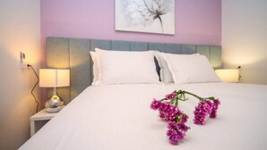 A neatly made bed with white linens and a bouquet of purple flowers on the bed. - Luxury Villa Jasmina with heated pool by the sea!!! (Omis)