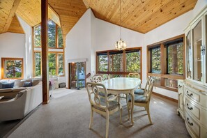 Una habitación amplia con un gran techo de madera, una mesa redonda de comedor con sillas, un sofá y un aparador.