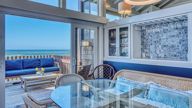 A spacious balcony with a view of the ocean, furnished with a sofa, chairs, and a glass table. - Oceanfront Retreat • Private Hot Tub • 3 King Suites + Loft • Walk to Beach (Castroville)