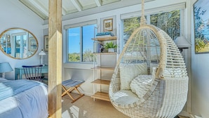 A bedroom with a hanging chair, a desk, a chair, and a bed. - Oceanfront Retreat • Private Hot Tub • 3 King Suites + Loft • Walk to Beach (Castroville)