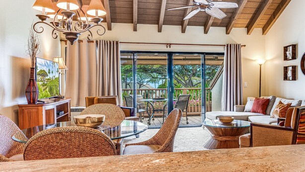 A spacious living room with a high ceiling, a ceiling fan, and a large sliding glass door leading to an outdoor area. - Top Floor Spacious Ocean View Condo! Minutes to Beaches, A/C, Wifi, Pool (Kihei)