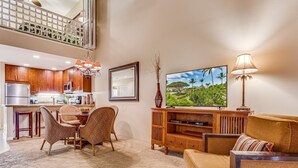 A spacious living room with a high ceiling, a kitchen area, and a dining set. - Top Floor Spacious Ocean View Condo! Minutes to Beaches, A/C, Wifi, Pool (Kihei)
