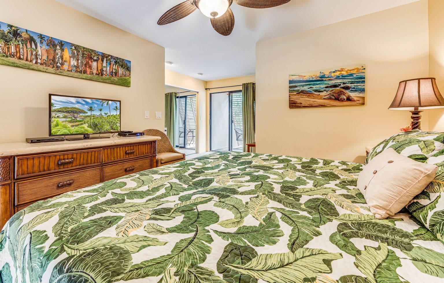 A bedroom with a bed, a dresser, a television, and artwork on the walls.