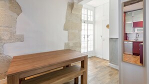 A room with a wooden table, a stone wall, and a view into a kitchen area. - Saint Paul, Marais History France Louis XIV &XV (Paris)