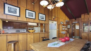 Interior de madera con cocina, barra y mesa de comedor.