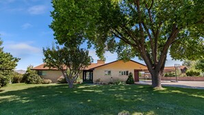 A two-story house with a brick exterior and a red roof, surrounded by a well-maintained lawn and trees. - Panoramic Views overlooking the Colorado River Valley (Grand Junction)