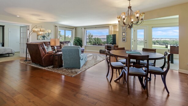 A spacious living room with a dining area, large windows, and a chandelier. - Panoramic Views overlooking the Colorado River Valley (Grand Junction)