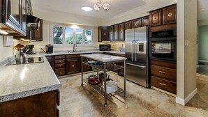 A modern kitchen with dark wooden cabinets, stainless steel appliances, and a granite countertop. - Panoramic Views overlooking the Colorado River Valley (Grand Junction)