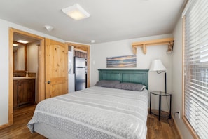 Un dormitorio con cama, armario de madera y una mesita de noche con lámpara.
