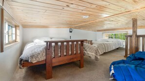 A bedroom with two wooden beds, a window, and a ceiling with wooden beams. - Fox Den at CrossTimbers Marina (Sperry)