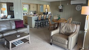 Ein Wohnzimmer mit Sofa, Sessel, Couchtisch sowie einem Essbereich mit Stühlen und Tisch.