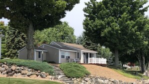 Ein Haus mit einer Veranda, einer Steinmauer und einem Fluss im Vordergrund.