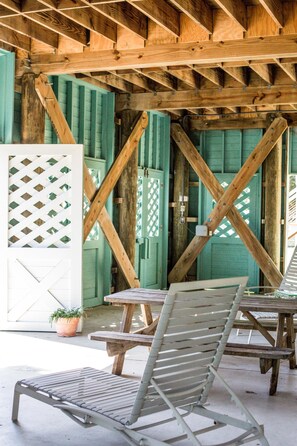Une structure en bois avec un plafond incliné, des portes vertes et une table entourée de chaises.