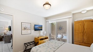 Een slaapkamer met een bed, een bureau, een stoel, een televisie en een kledingkast.