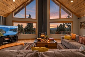 A cozy living room with a fireplace, large windows, a television, and comfortable seating. - Pet-Friendly | Mountain Views | Games | Rec Center Access | Near Trails (Truckee)
