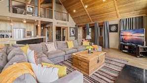 A spacious living area with a large sectional sofa, a wooden coffee table, and a flat-screen TV. - Pet-Friendly Mountain View Retreat | Near Lake & Trails | Rec Center Access (Truckee)