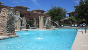 A swimming pool with stone pillars, lounge chairs, and a clear blue sky. - WELL DRESSED GRAYHAWK CONDO! QUIET OPEN BRIGHT...Close to all the good stuff! (Scottsdale)