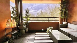 A balcony with a wicker sofa, a small table, a floor lamp, and potted plants. - WELL DRESSED GRAYHAWK CONDO! QUIET OPEN BRIGHT...Close to all the good stuff! (Scottsdale)