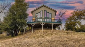 A two-story house with a balcony, surrounded by trees and dry grass. - Custom Built by the Littlehale Family (Julian)