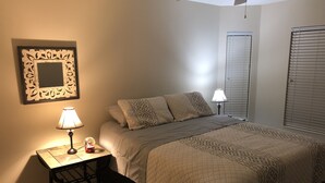 A bedroom with a bed, bedside lamps, a small table, and a decorative mirror. - Golfer’s Paradise 3/2 Luxury Vacation Home (Bradenton)
