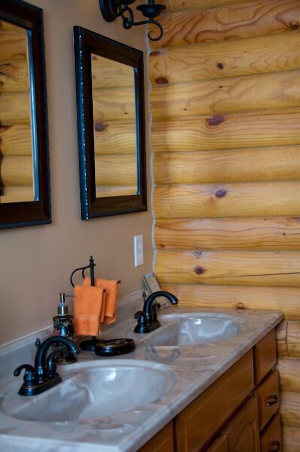 A bathroom with wooden paneling, two mirrors, a double sink, and a towel rack.