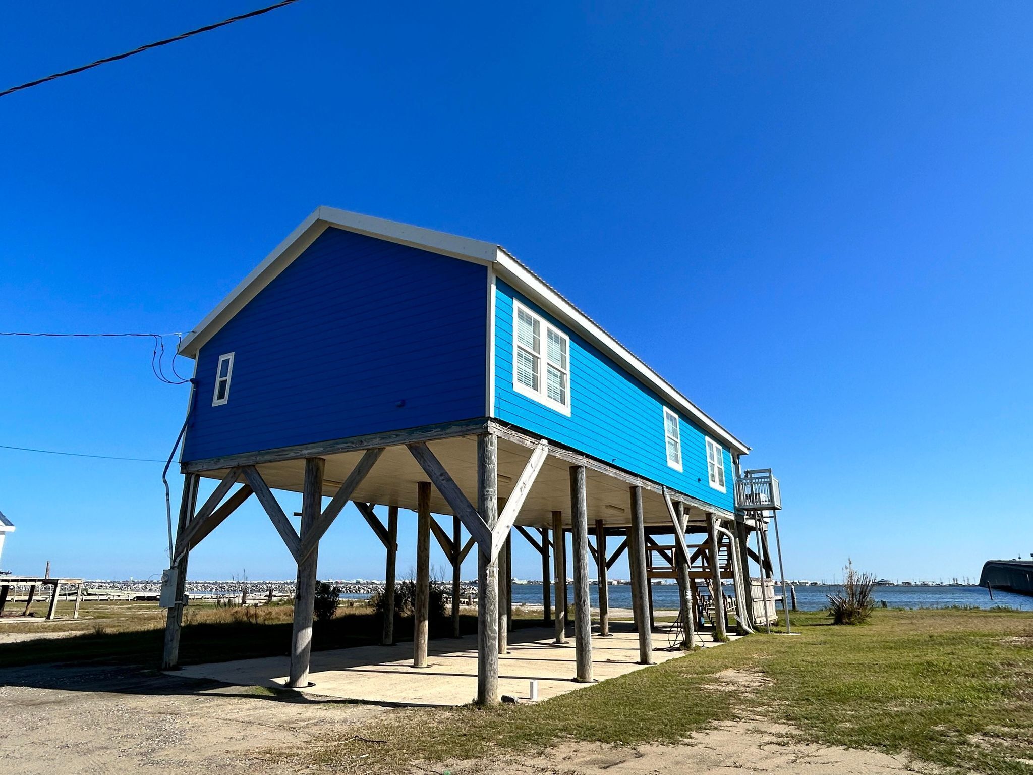 A blue house with a wooden deck and a view of the water.