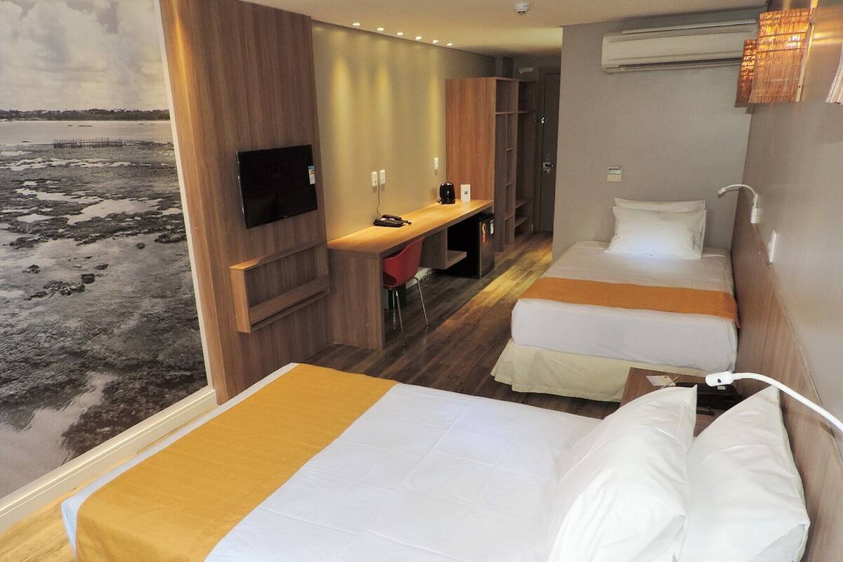Une chambre d’hôtel avec deux lits, un bureau et une télévision.