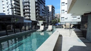 A swimming pool with lounge chairs and a glass railing, surrounded by modern buildings. - Comfort Hotel Maceio (Maceió)