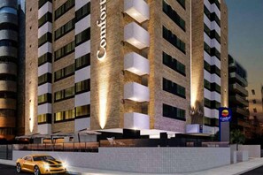 A hotel with a modern design, featuring a prominent 'Comfort' sign on the facade, multiple balconies, and a well-lit entrance. - Comfort Hotel Maceio (Maceió)