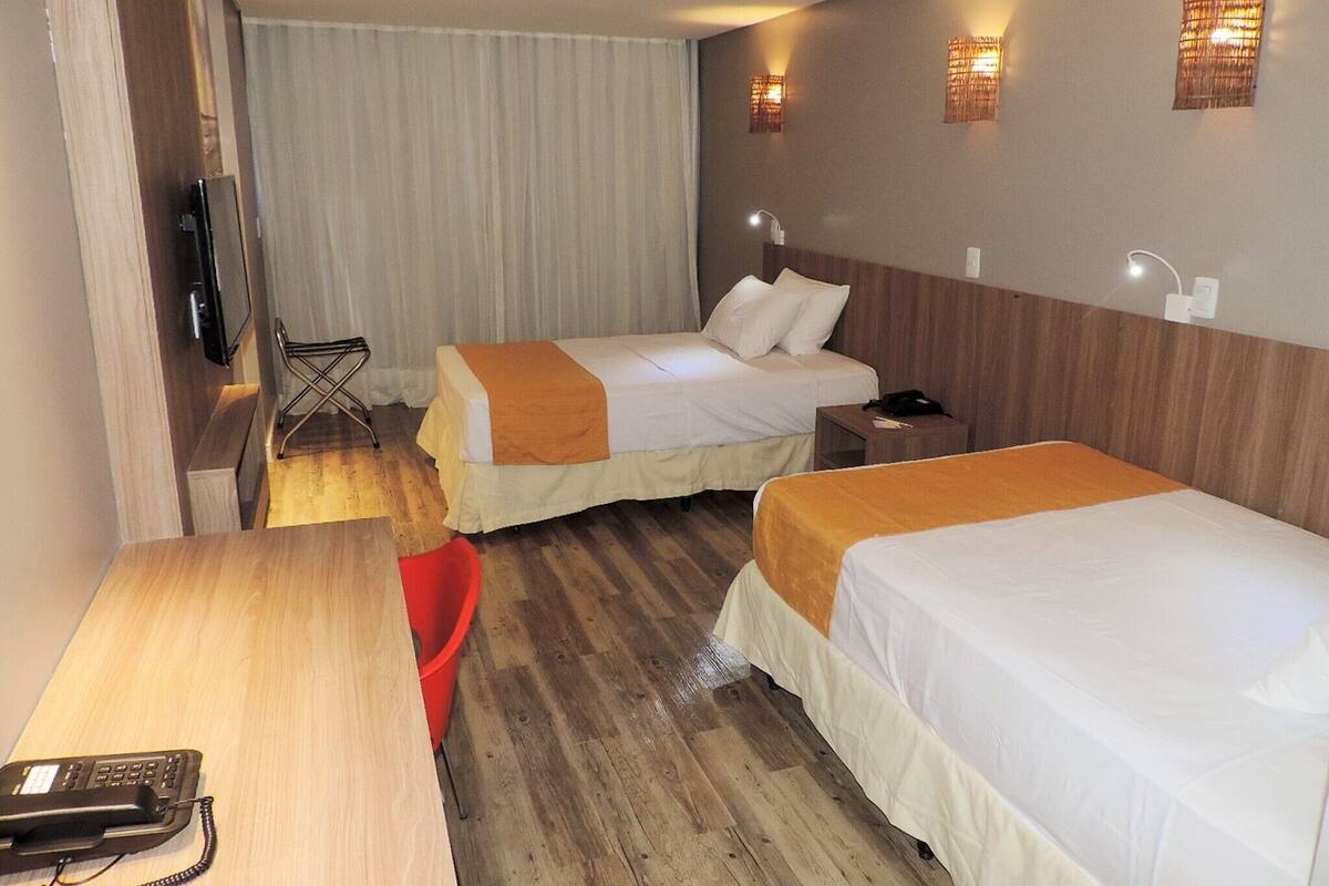 Une chambre d’hôtel avec deux lits, un bureau, un téléphone et une chaise.