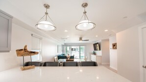 Une cuisine spacieuse dotée d’un grand îlot central, de luminaires suspendus et donnant sur la salle à manger.