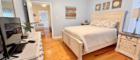 A bedroom with a bed, dresser, desk, and a ceiling fan.