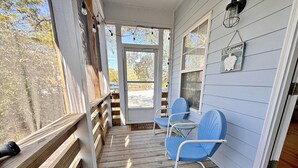 Eine Veranda mit Holzgeländern, zwei blaue Stühle und einem 'Welcome'-Schild.