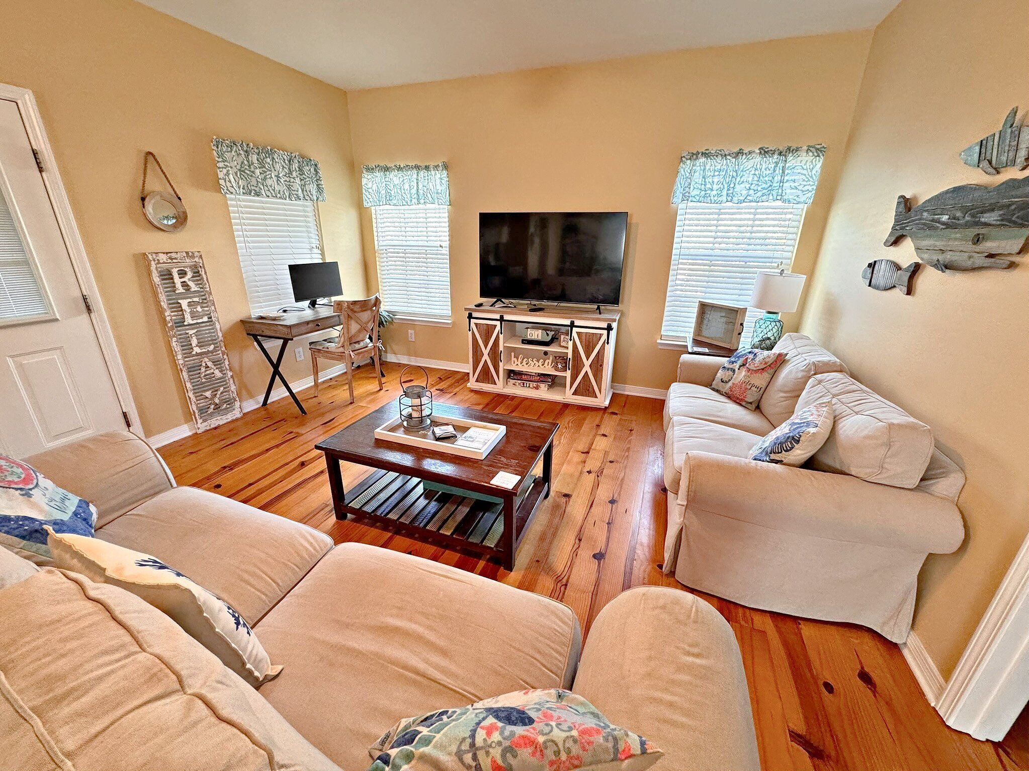 A living room with a TV, a coffee table, two sofas, and a desk with a computer.