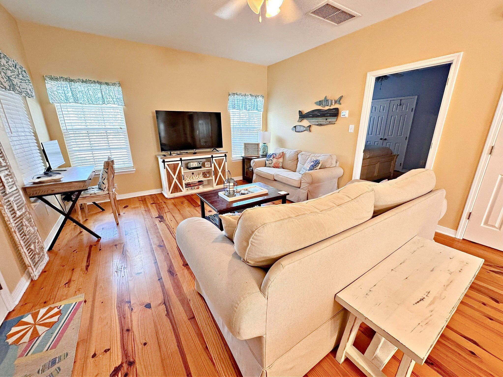 A living room with a sofa, a coffee table, a TV on a stand, and a door with a fish decoration.