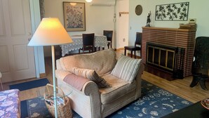 Una sala de estar con un sofá, una lámpara, una chimenea y un comedor al fondo.