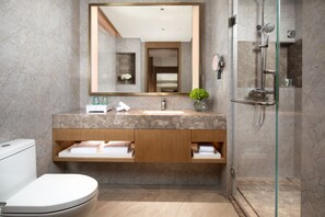 A modern bathroom with a marble vanity, a glass shower enclosure, and a toilet.