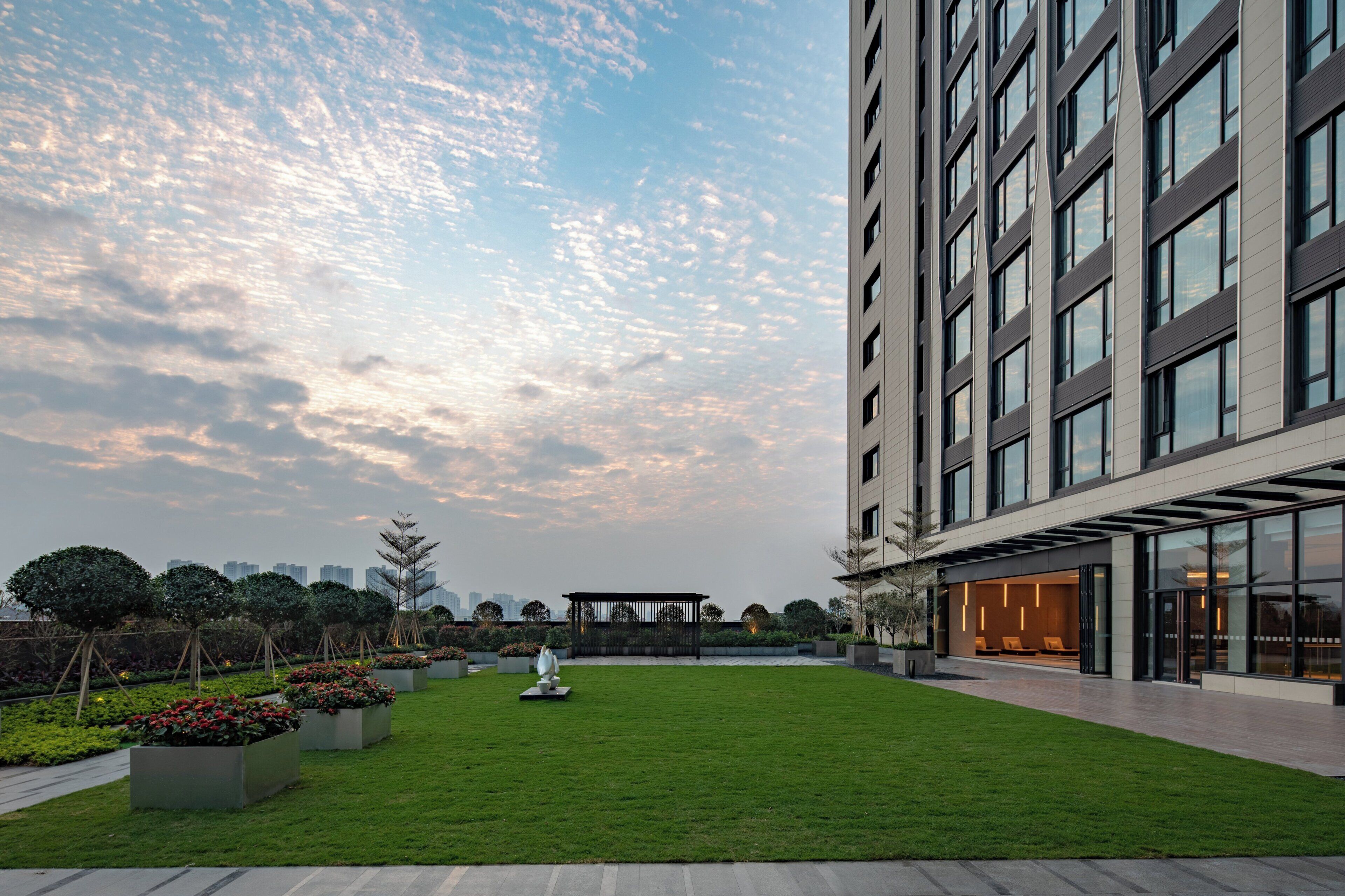 A modern building with a well-maintained lawn and a seating area with a sculpture.