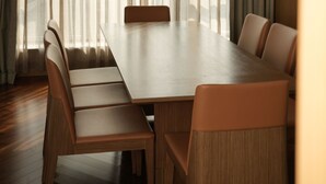 Comedor con mesa de madera y seis sillas, ventanas amplias con cortinas ligeras y una lámpara colgante.