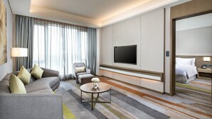 Una habitación de hotel moderna con sofá, sillón y televisor fijado a la pared.