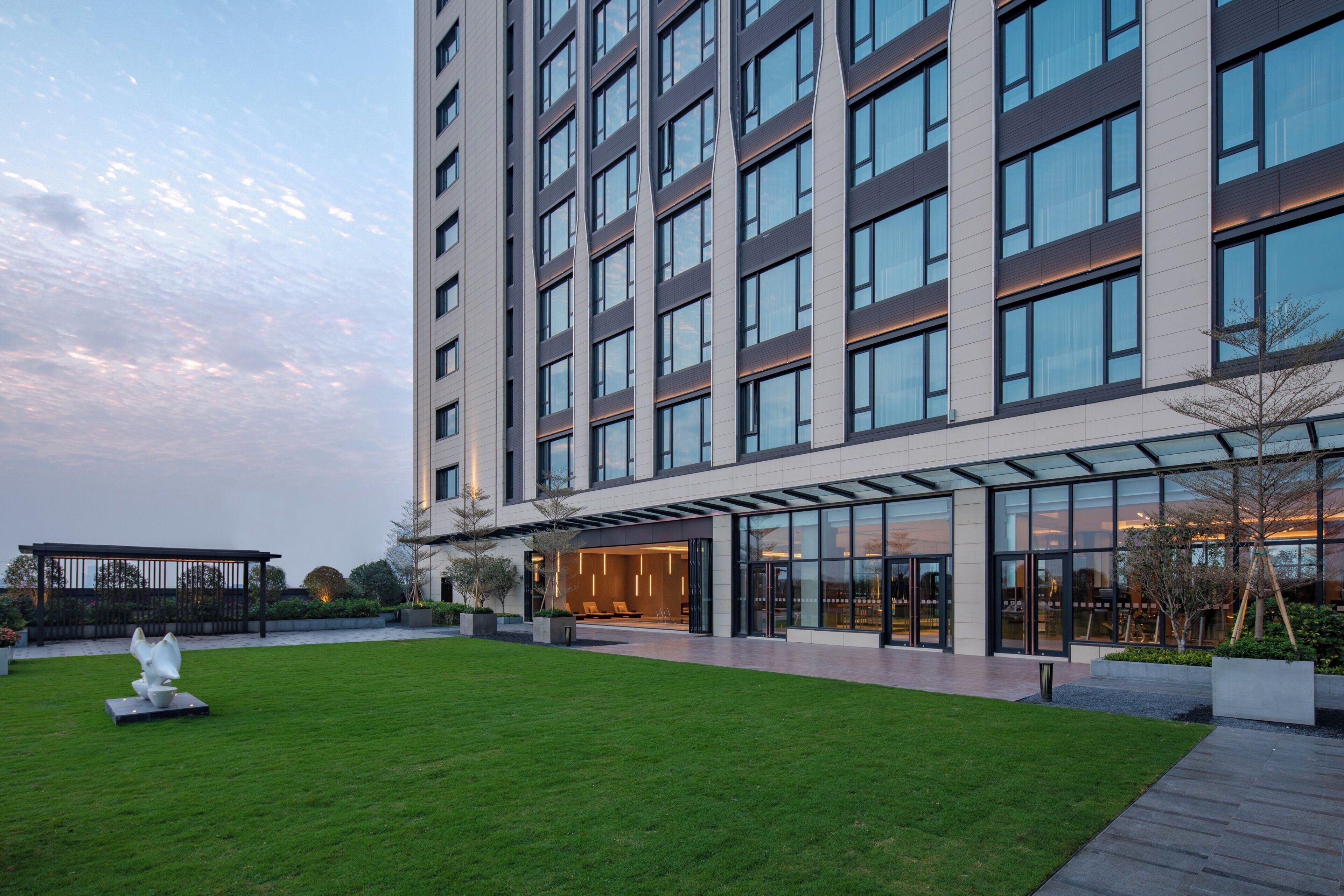 A modern building with a flat roof, large windows, and a well-maintained lawn.