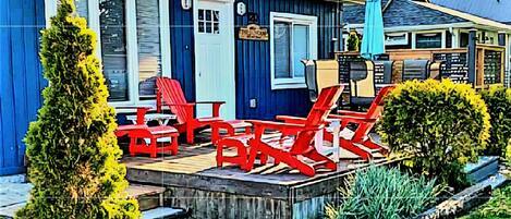 A house with a deck, red chairs, and a blue umbrella.